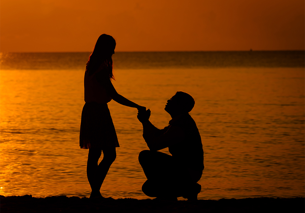 夕べの海辺で男性からプロポーズを受ける女性
