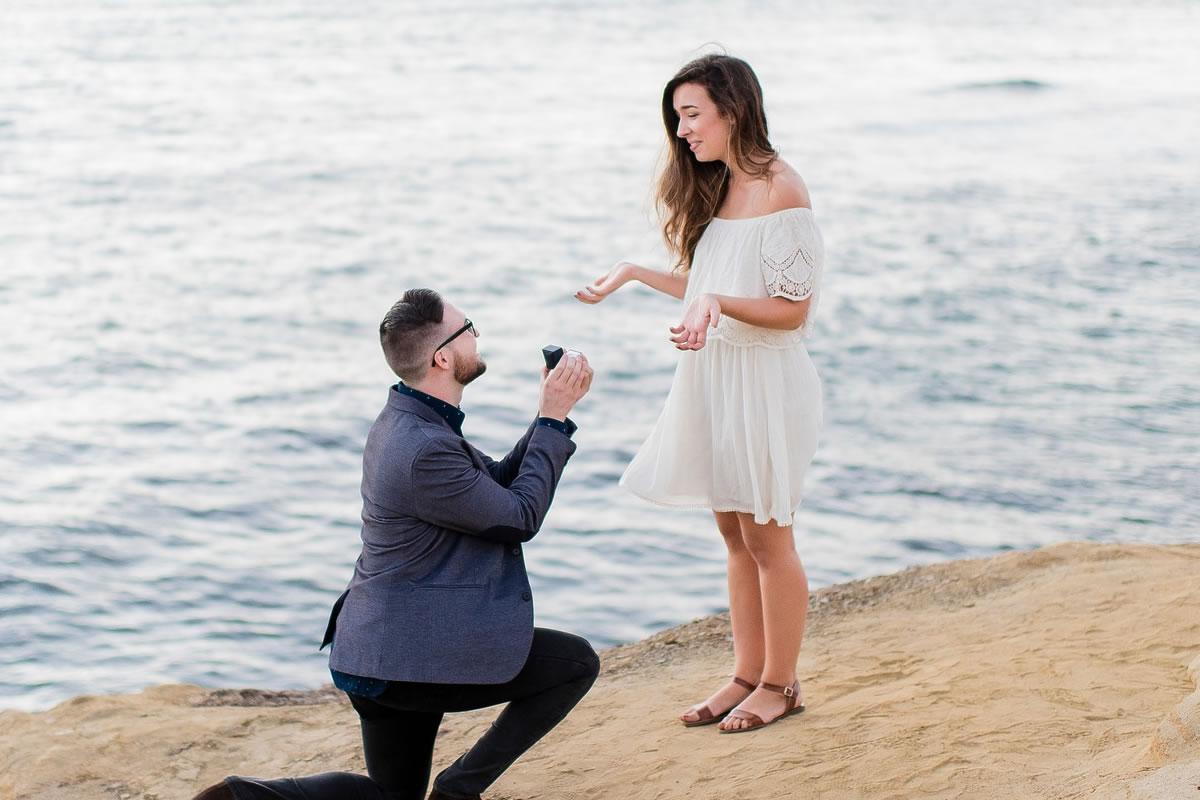 砂浜でプロポーズをするカップル
